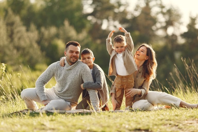 Loving family with two young son playing in summer field